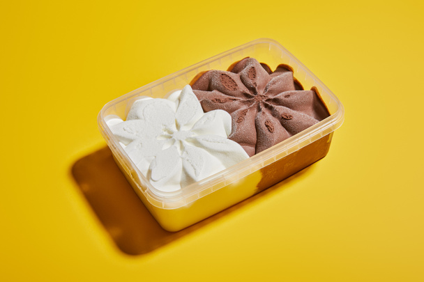 vers smakelijk bruin en wit ijs in container op gele achtergrond - Foto, afbeelding