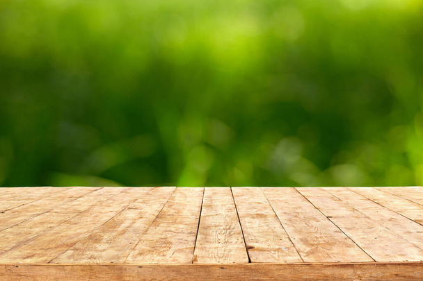 Empty wooden deck table with foliage bokeh background. Ready for product display montage. - Фото, зображення