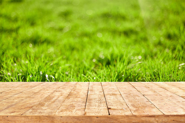 Empty wooden deck table with foliage bokeh background. Ready for product display montage. - Φωτογραφία, εικόνα