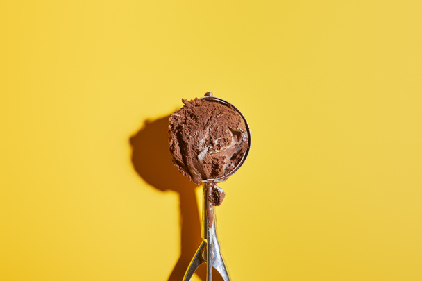 top view of fresh chocolate ice cream ball in scoop on yellow background - Foto, Bild