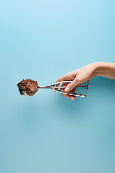 vue recadrée de femme tenant cuillère avec crème glacée au chocolat sur fond bleu
 - Photo, image