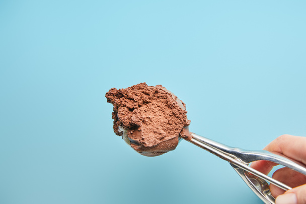 vista cortada de mulher segurando colher com sorvete de chocolate no fundo azul
 - Foto, Imagem