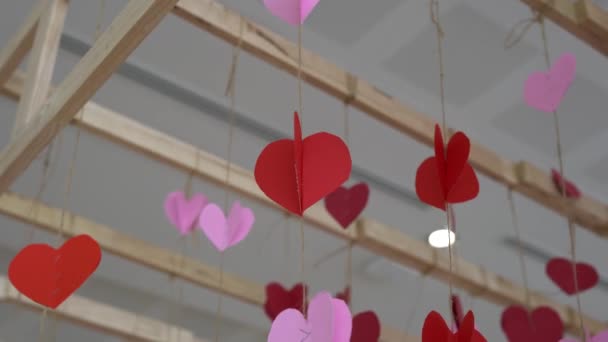 Rode papieren hart hangend aan een rode snaar met hartjes deeltjes - Video