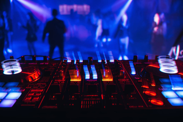Mélangeur DJ dans une boîte de nuit avec des lumières colorées brillantes des contrôleurs et des boutons
 - Photo, image