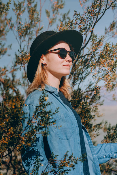 Kaliforniya 'daki Ölüm Vadisi Ulusal Parkı' nda geniş kenarlı keçeli şapkalı bir kızın portresi. Ölüm Vadisi çölünde poz veren mavi gömlekli bir gezgin kız. - Fotoğraf, Görsel