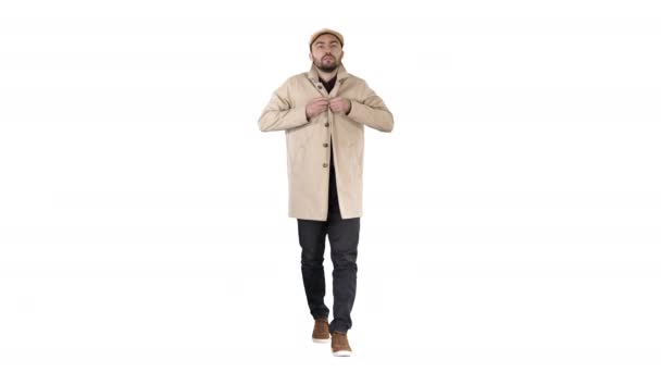 Jonge knappe man loopt en knoppen omhoog mantel op witte achtergrond. - Video