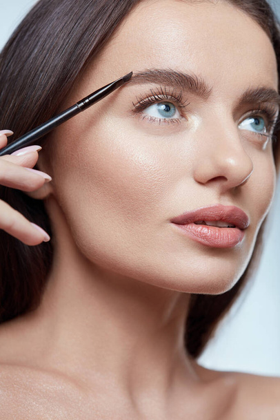 Eyebrows Makeup. Woman Shaping Brow With Cosmetic Brush. Beautiful Girl Close Up Portrait. Brunette With Perfect Skin And Blue Eyes. - 写真・画像