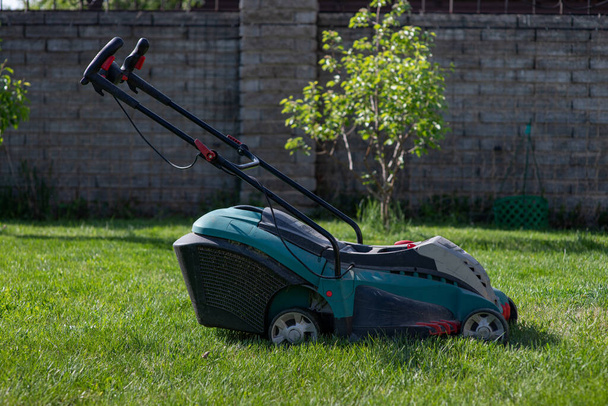 芝刈り機を持った男が草を刈る。裏庭の世話をしてる。滑らかな美しい緑の芝生。庭園/庭園 - 写真・画像