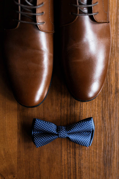 Men's accessories, perfume, boutonniere, gold rings, watches and leather shoes of the groom on a wooden table. Businessman clothing detail concept. Luxury men's accessories. Stylish men's shoes. - Foto, imagen