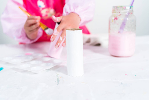 Kleines Mädchen bastelt aus Toilettenpapierrolle und Bastelpapier ein Einhorn. - Foto, Bild