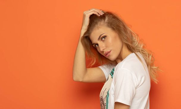 Portrait of a young woman on orange background. - Foto, afbeelding