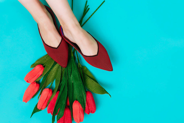Beautiful female legs are dressed in stylish burgundy flat shoes. Burgundy sandals on a blue background. - Φωτογραφία, εικόνα