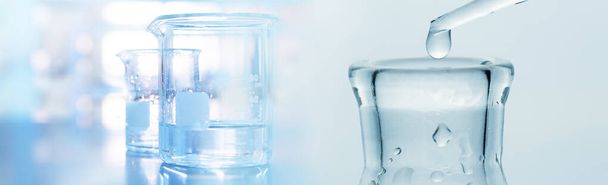 waterdruppel in onderzoeksglazen kolf en beker in zacht blauw licht medische wetenschap laboratorium banner achtergrond - Foto, afbeelding