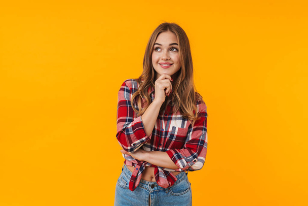 Image of happy young attractive woman wearing plaid shirt smiling isolated over yellow background - Photo, image