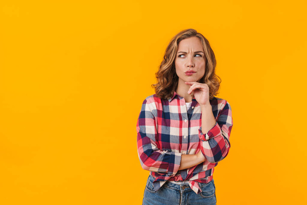 Image of young beautiful woman wearing plaid shirt expressing concern isolated over yellow background - Foto, afbeelding