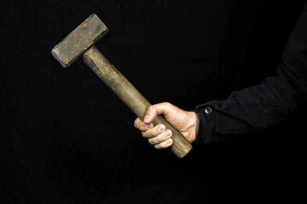 sledgehammer, hammer in the hand of a worker on a black background - Fotó, kép