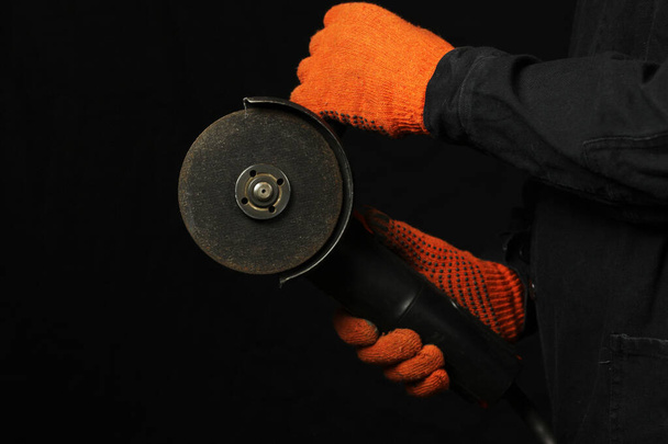 Un hombre sostiene una sierra eléctrica en sus manos sobre un fondo negro
 - Foto, Imagen