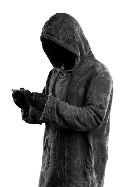 Хакер держит смартфон. Темное лицо. Изолированный на белом фоне
 - Фото, изображение