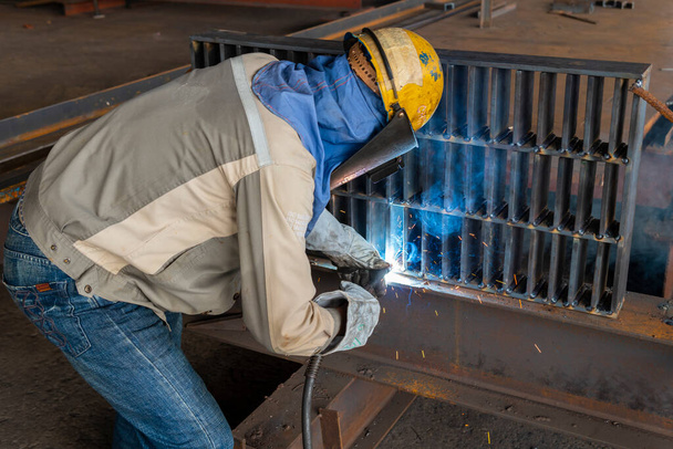 A hegesztő hegesztés acélszerkezet munka folyamat Flux Cored Arc hegesztés (FCAW) és megfelelően öltözött egyéni védőfelszerelés (PPE) a biztonság érdekében, az ipari üzemben. - Fotó, kép