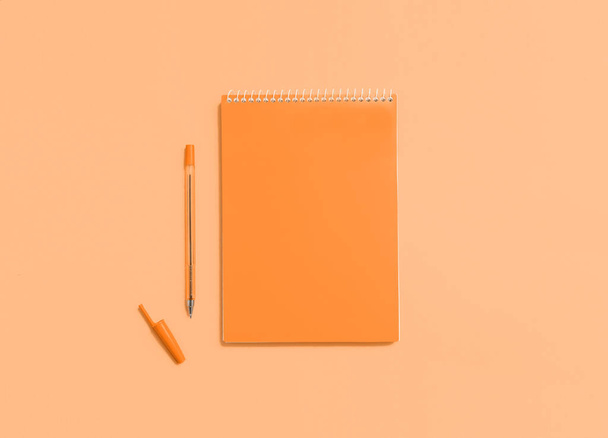 Mock up, orange color notebook and pen on blue background. - Photo, image
