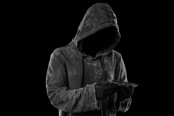 Hacker sosteniendo smartphone. Cara oscura. Aislado sobre fondo negro
 - Foto, Imagen