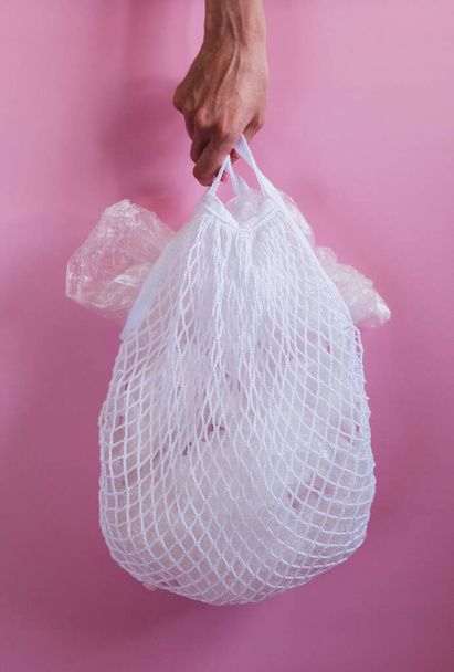 Plastic bags in a string bag on pink background. - Foto, afbeelding
