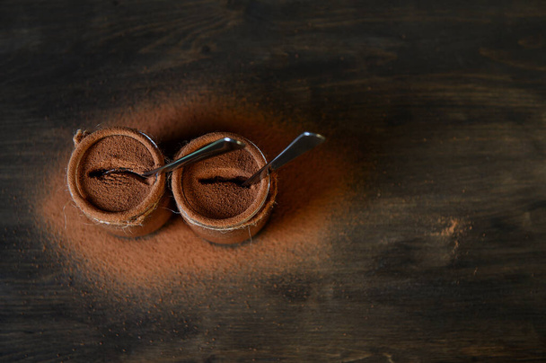 Chocolademousse in kleine potjes op een houten ondergrond met gestrooide cacao. Selectieve focus. - Foto, afbeelding