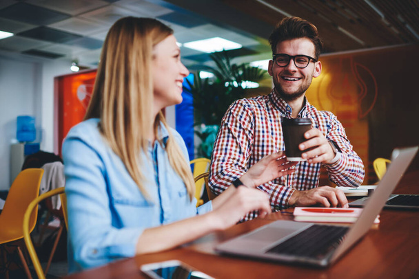 Happy male and female rest sitting in workplace in office enjoying time for communicate indoors, Caucasian cheerful it specialists leave laptops modern technology to have break and drink coffee - Zdjęcie, obraz