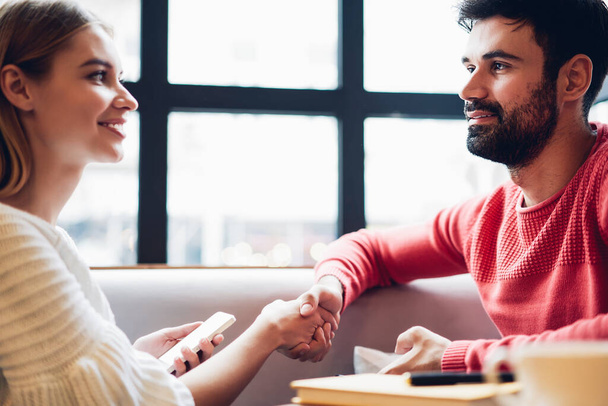 Caucasian woman shaking hand of male colleague happy with good deal agreement, happy successful hipster guys discussing startup project details during business meeting for communicate indoors - Foto, Imagem