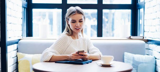 Attractive hipster girl typing text for search information about online blogging during networking social websites via cellular phone, beautiful woman editing media pictures via smartphone photo app - 写真・画像