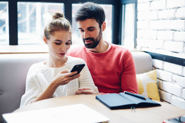 Millennial couple in love checking travel publications in social networks for planning trip togetherness using 4g wireless internet on modern cellphone gadget, marriage watching online video - Photo, Image