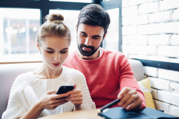 Millennial couple in love checking received messages in social networks using 4g wireless internet on modern smartphone gadget, Caucasian marriage watching online video analyzing popular content - Foto, Bild