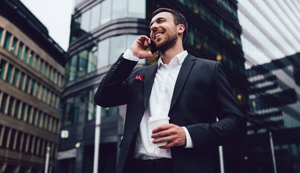Happy man in formal wear calling to friend for communicate during business work break in financial district using 4g roaming international connection from operator system, concept of service talking - Fotoğraf, Görsel