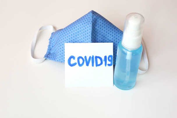 Cloth cotton face mask and antibacterial gel sanitizer to prevent coronavirus Covid 19. Hand made face mask blue color on white background. - Photo, image