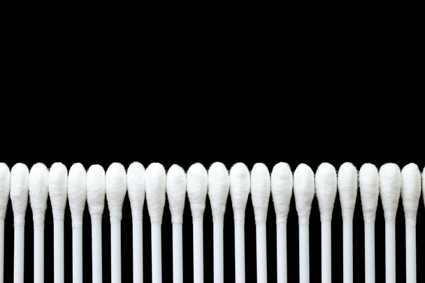 White cotton buds are arranged in an orderly and beautiful way on a black background. - Photo, Image