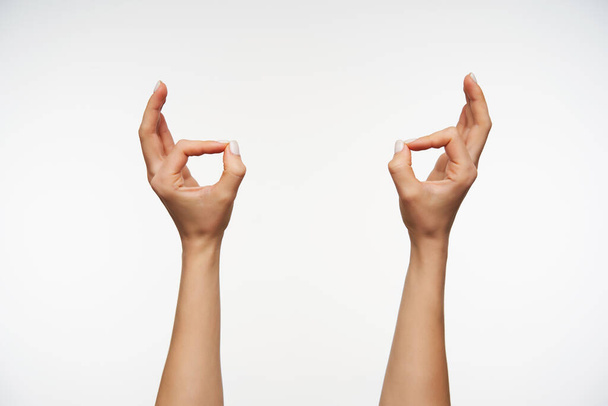 Wewnętrzne zdjęcie dłoni młodej damy z białym manicure tworzącym gest murda podczas pozowania na białym tle. Kobiety pokazujące dłonie z językiem migowym - Zdjęcie, obraz