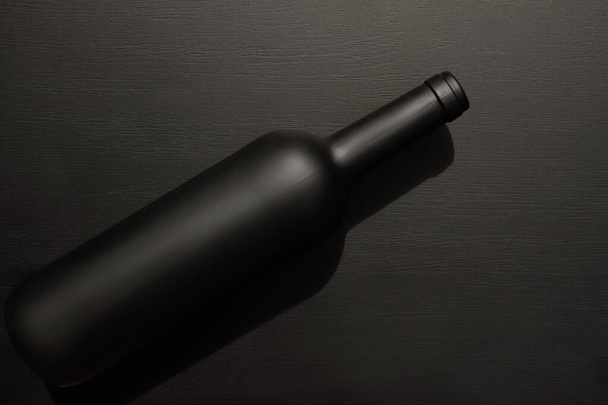 botella de vino negro mate que pone sobre fondo negro, mesa, vista superior, espacio de copia
  - Foto, Imagen