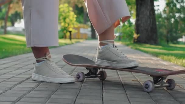 Όμορφο πόδι μιας γυναίκας σε μπεζ sneakers σταθεί σε ένα skateboard - Πλάνα, βίντεο