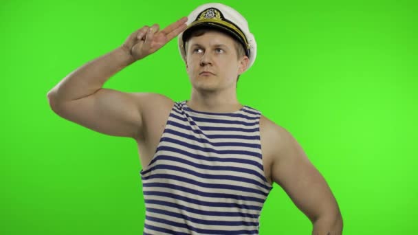 Young sailor man salutes with hand, looking up. Seaman guy in sailors vest - Footage, Video