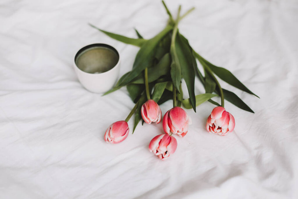Coffee cup and tulips in bed. Concept of holiday, birthday, Women Day. Breakfast in bed. Good morning. still life, flat lay - Foto, Imagen