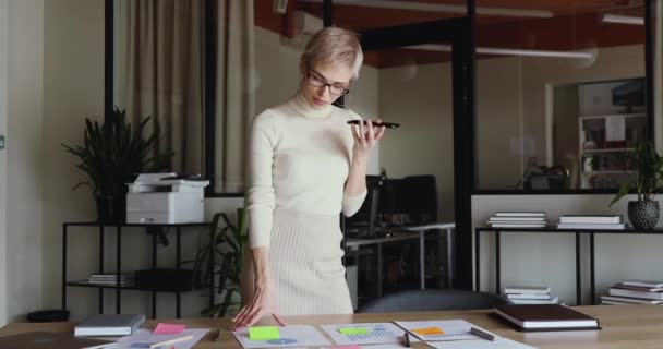 Young businesswoman working on project plan recording mobile voice memo - Кадри, відео