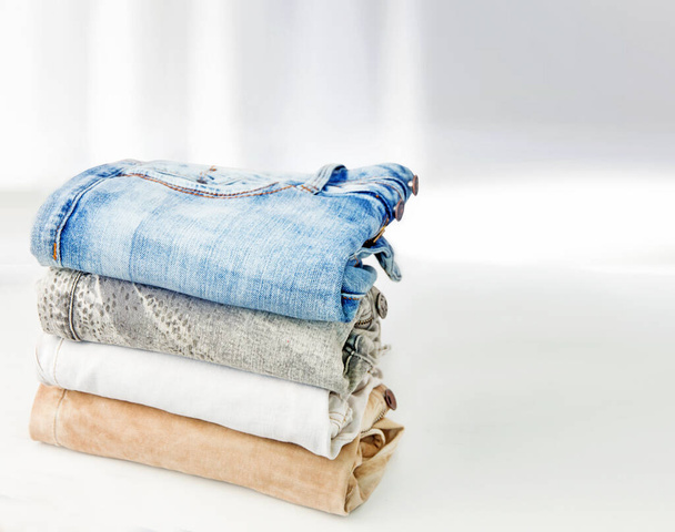 Pile of jeans on a white table - Photo, Image