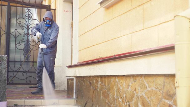 Человек в маске управляет домом с помощью мойки высокого давления
 - Фото, изображение
