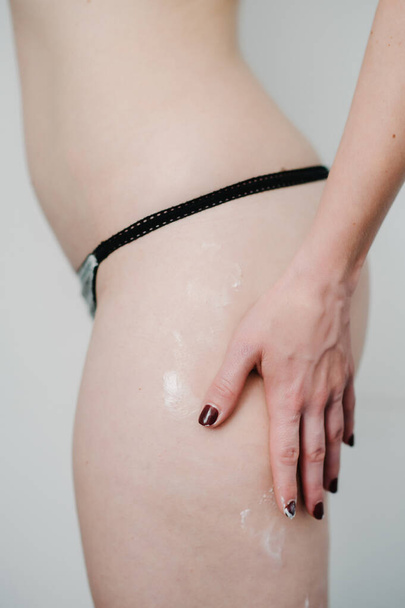 Sexy beautiful woman applying moisturizer cream on her body, thighs after shower. Photo girl with flawless skin isolated on gray background. Close up. Skin care and beauty concept. Cosmetology. - Φωτογραφία, εικόνα