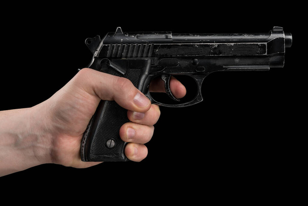 Πιστόλι Beretta M9 σε αρσενικό χέρι απομονωμένο σε μαύρο φόντο.  - Φωτογραφία, εικόνα