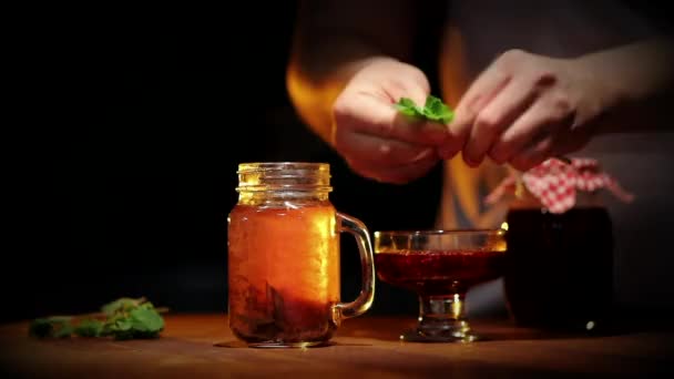 fresh black tea in glass jar with mint leaves on wooden table - Felvétel, videó