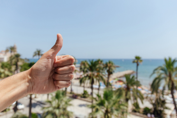 Widok człowieka pokazującego podobny gest palmami i wybrzeżem morza na tle Katalonii, Hiszpania - Zdjęcie, obraz