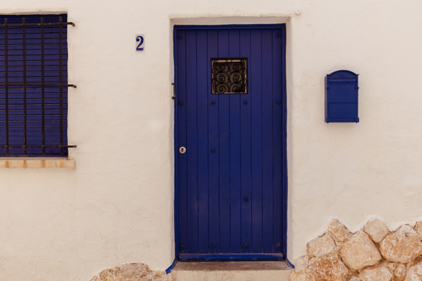 Синя поштова скринька та дерев "яні двері біля будинку в Каталонії (Іспанія).   - Фото, зображення