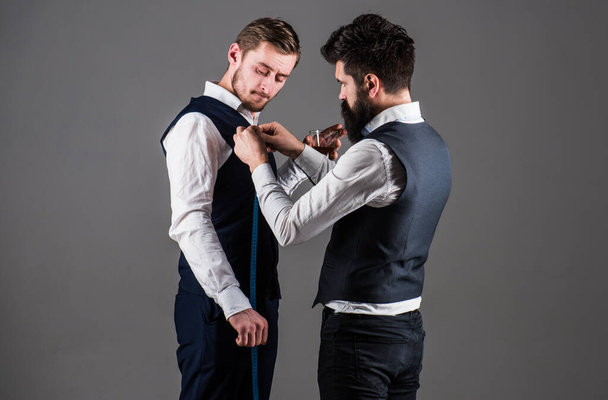 Tailor taking measurements for sewing, grey background. - Φωτογραφία, εικόνα