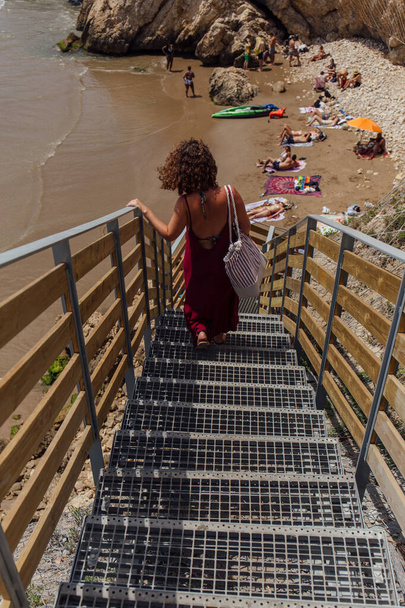 KATALONIEN, SPANIEN - 30. April 2020: Selektiver Fokus von Frauen, die auf Treppen am Strand mit Steinen gehen  - Foto, Bild